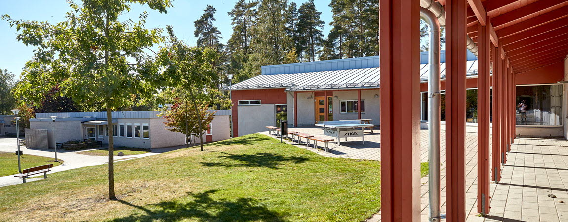 Bild på Högstorps skola. En röd byggnad med gräsyta framför. 